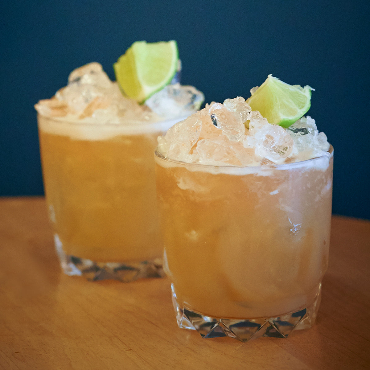 two drinks topped with lime wedges