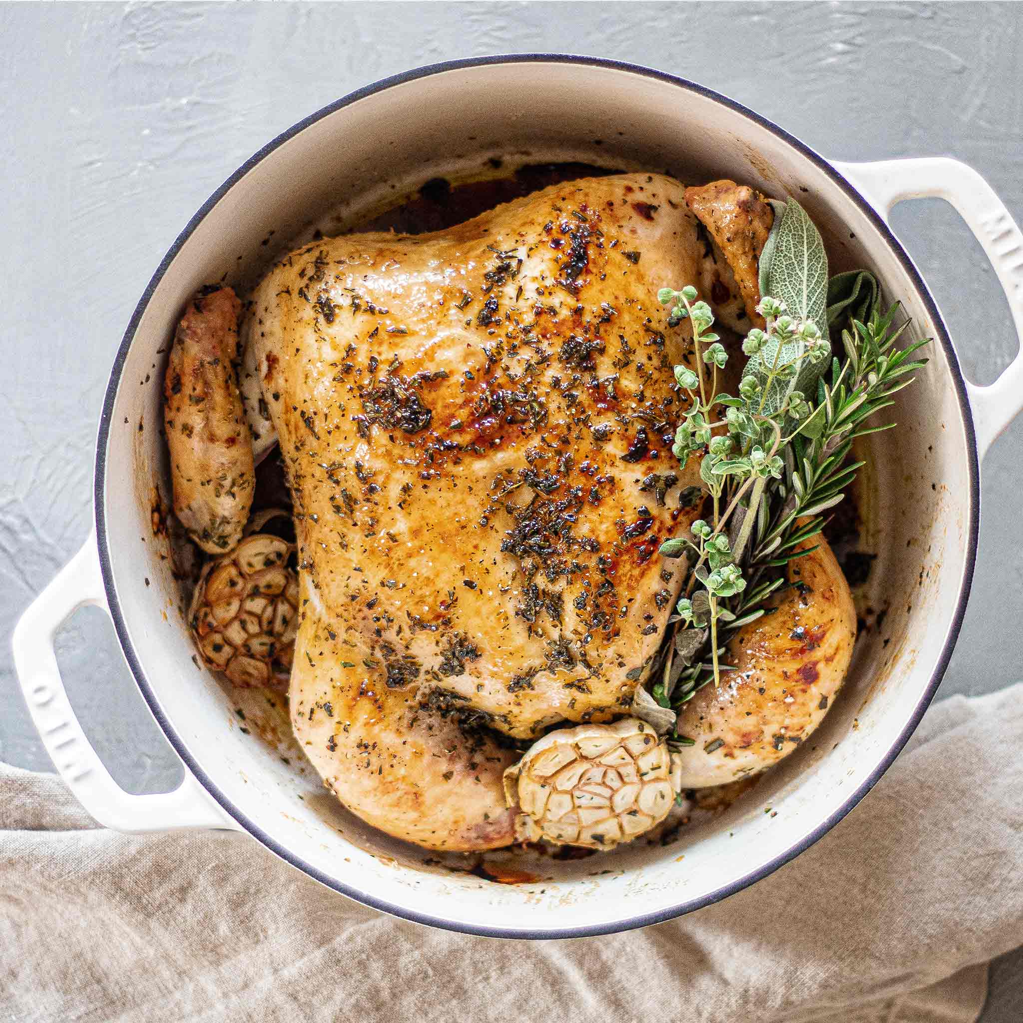Whole roast chicken in Dutch oven with herbs, garlic and honey.