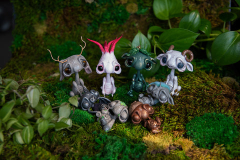 Eight handsculpted adult and baby mishes on bed of moss.