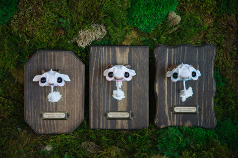 Yeti mish heads on wood wall mounts in front of bed of moss.