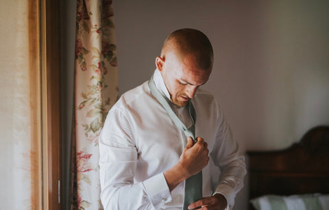 Groom tying a wedding tie