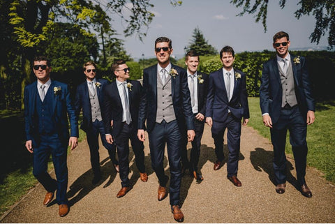 Groomsmen and groom wearing wedding suits and ties in the sunshine