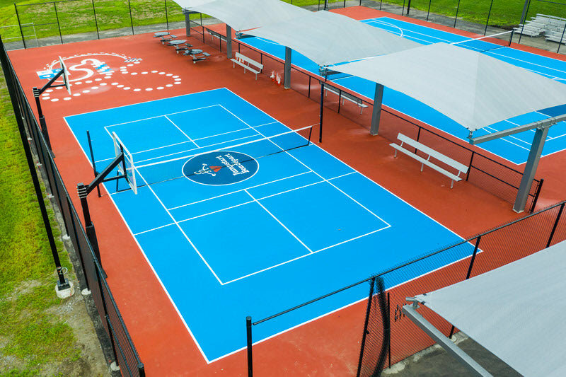 A photo of the Jumpstart Inclusive Multi Sport Court in Uxbridge, Ontario showing one of the courts which has a tennis net setup with basketball nets at the side.