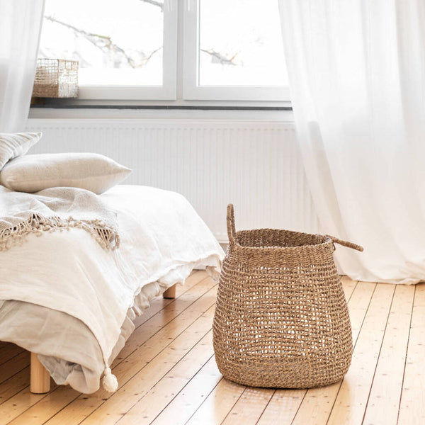 Großer Wäschekorb aus Seegras mit Henkeln im Schlafzimmer