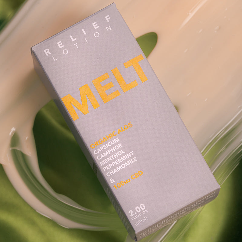 Kush Queen Melt CBD Relief Lotion shown in its packaging laying on a green silk.