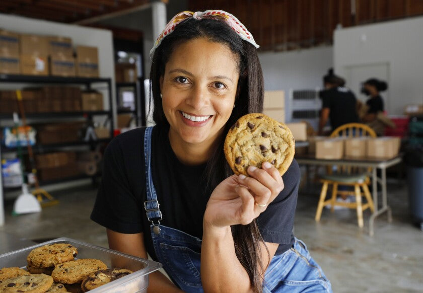 Maya Madsen, founder of Maya’s Cookies, a gourmet vegan cookie company in San Diego, holds a cookie at her bakery.