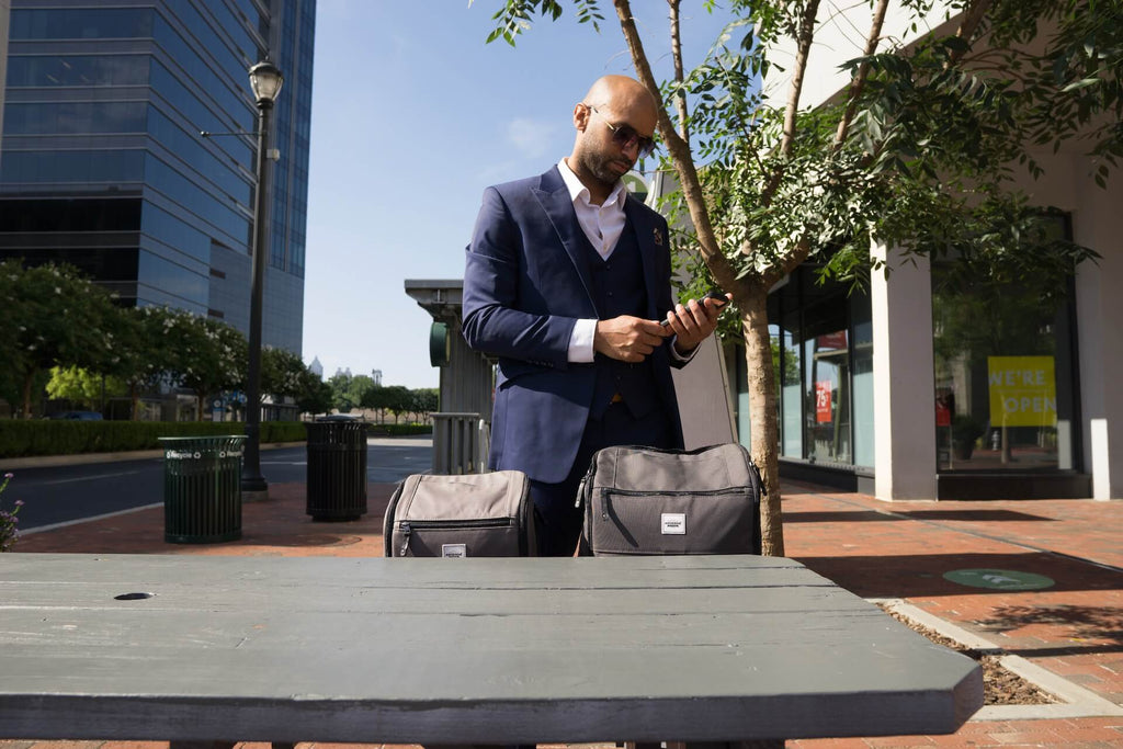 Man in front of a wooden table in the street, two Anvanda bags on the bench next to him