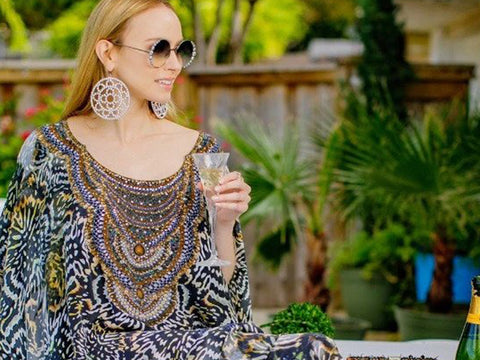 An image of a woman sitting on a table with a glass of champagne in her hand.