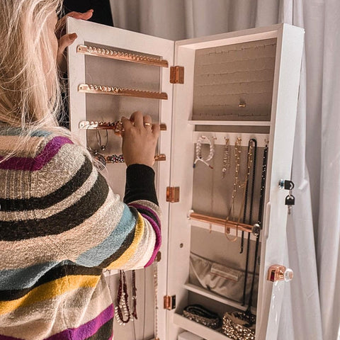 A woman organizing her jewelry in a Jewelry Armoire from LUXFURNI
