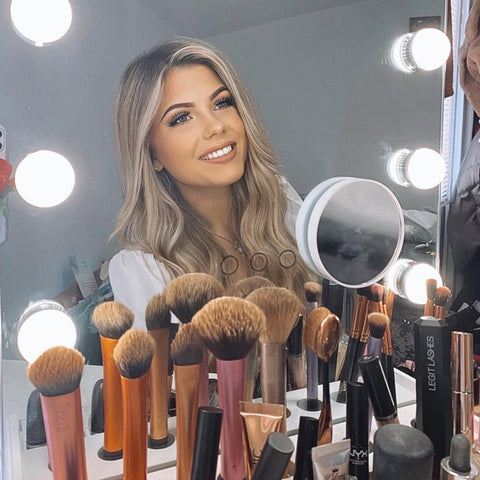 A beautiful woman doing her makeup in front of LUXFURNI Makeup Mirror with Built-in Storage