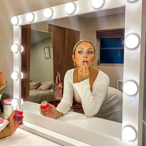 A woman putting her lipstick in front of an anti glare makeup mirror