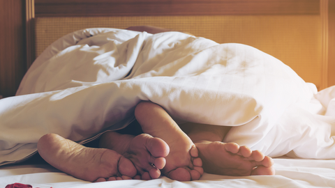 Two pairs of feet in bed