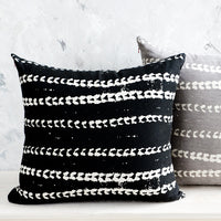 2: Two square throw pillows, one black and one grey, with white batik printed stripes.