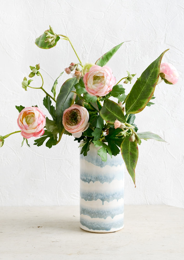 A blue and white vase with ranunculus arrangement.