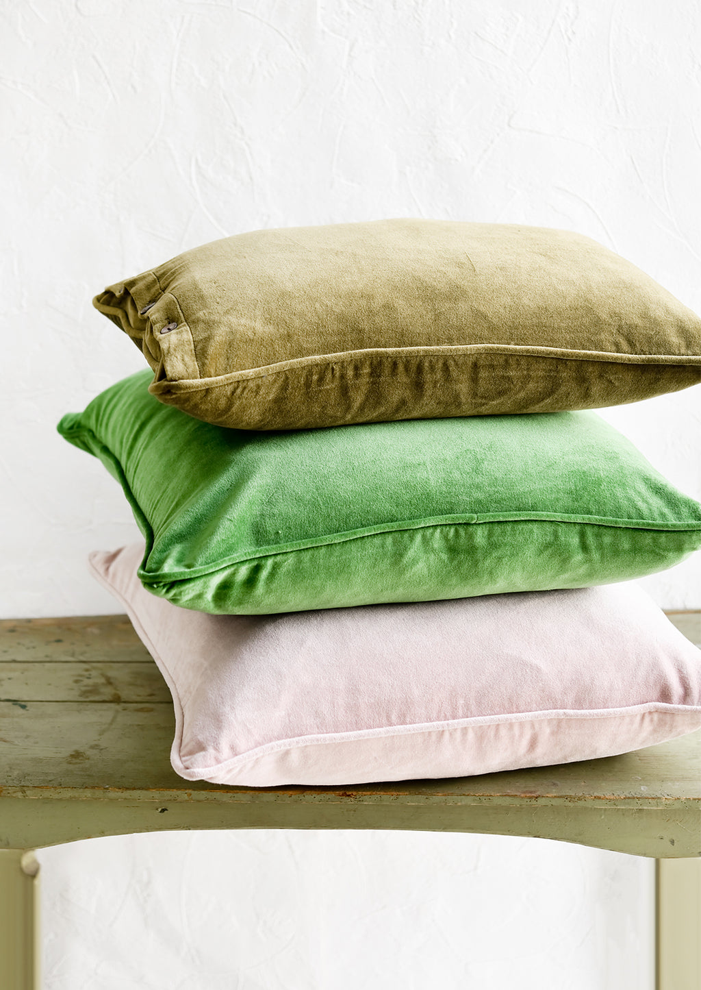 1: A stack of velvet pillows in green and pink.