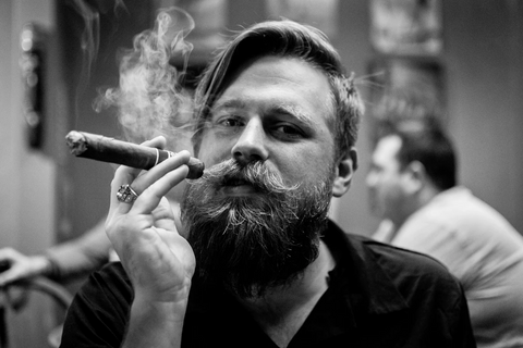 A bearded man smoking a cigar