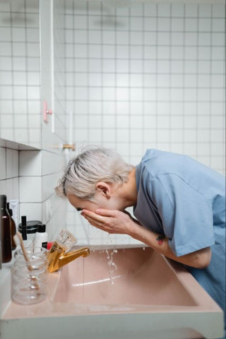 Man in blue t-shirt washing his face