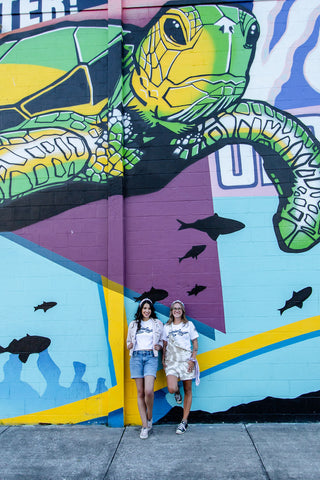 Jaclyn and Yasmin standing in front of a sea turtle mural