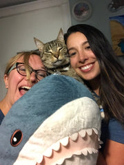 Photo of Jaclyn and Yasmin and their cat holding a plush shark