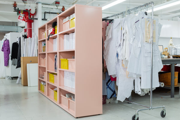 Bookcases and baskets next to a clothing rack of patterns