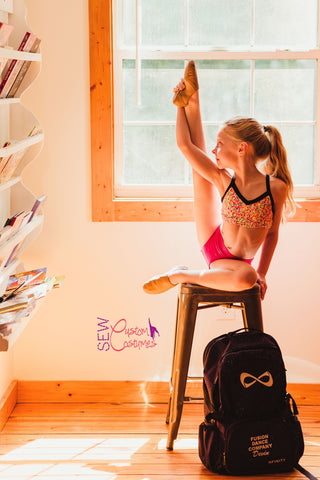 dancer holding up one leg while sitting on stool