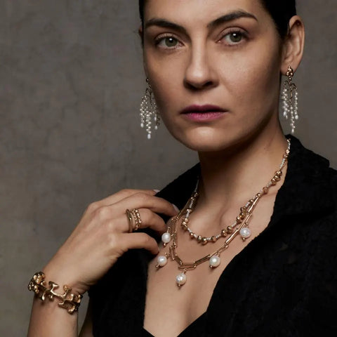 A model wearing Julie Cohn jewelry, including the Wisteria pearl and bronze earrings and Inca cuff.