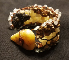 Twisted copper wire bracelet with brown, yellow, and tan stones and a black y-shaped wire in the center, with a large triangular yellow-ish stone at the end.