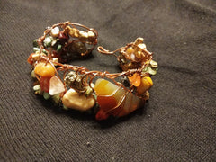 Copper twisted wire bracelet with stones of varying colors of orange, yellow, cream, and beige.
