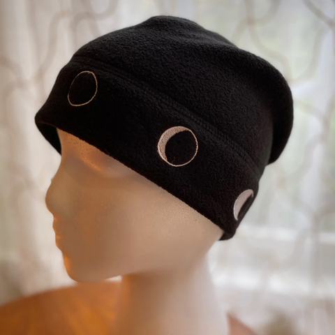Mannequin wearing a black beanie with white moon phases