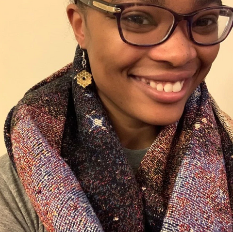 A woman with glasses wearing a scarf covered in a nebula print