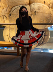 Woman with dark hair and a face mask wearing a long sleeve black shirt and a red and white skirt in the geometric design of the Perseverance Rover Parachute.