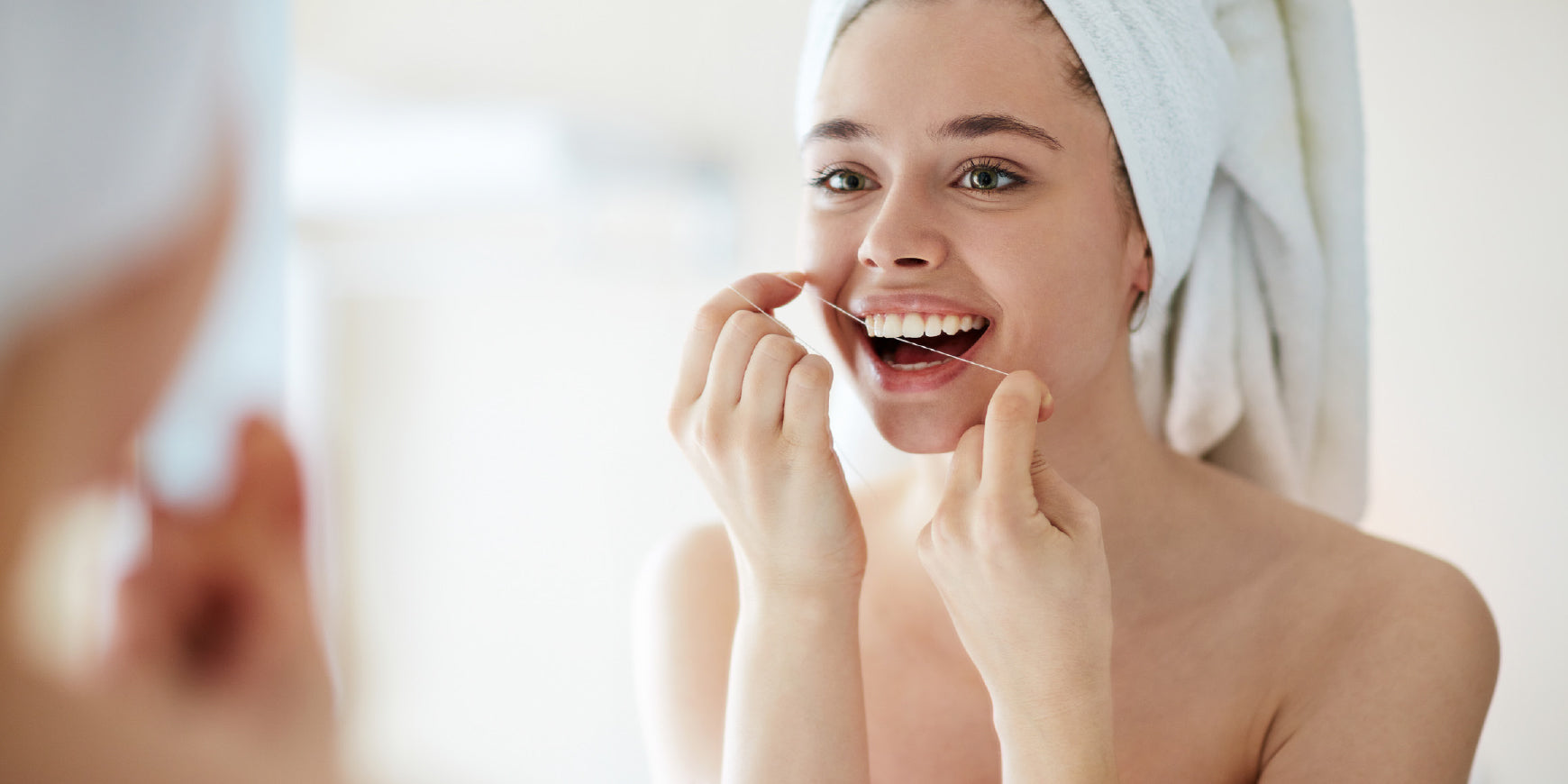 Woman flossing in mirror