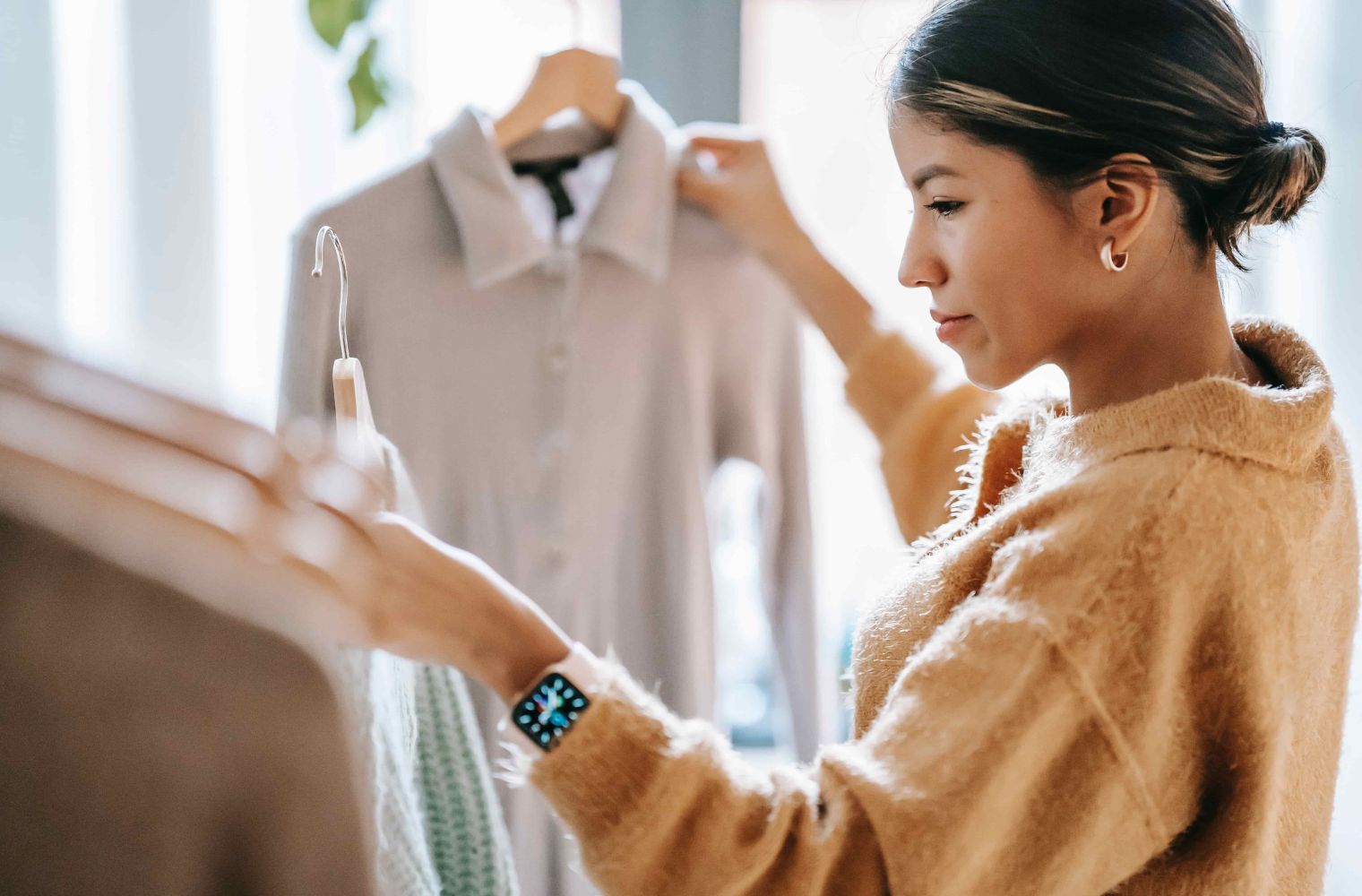 Woman holding up clothes on hangers and looking at them