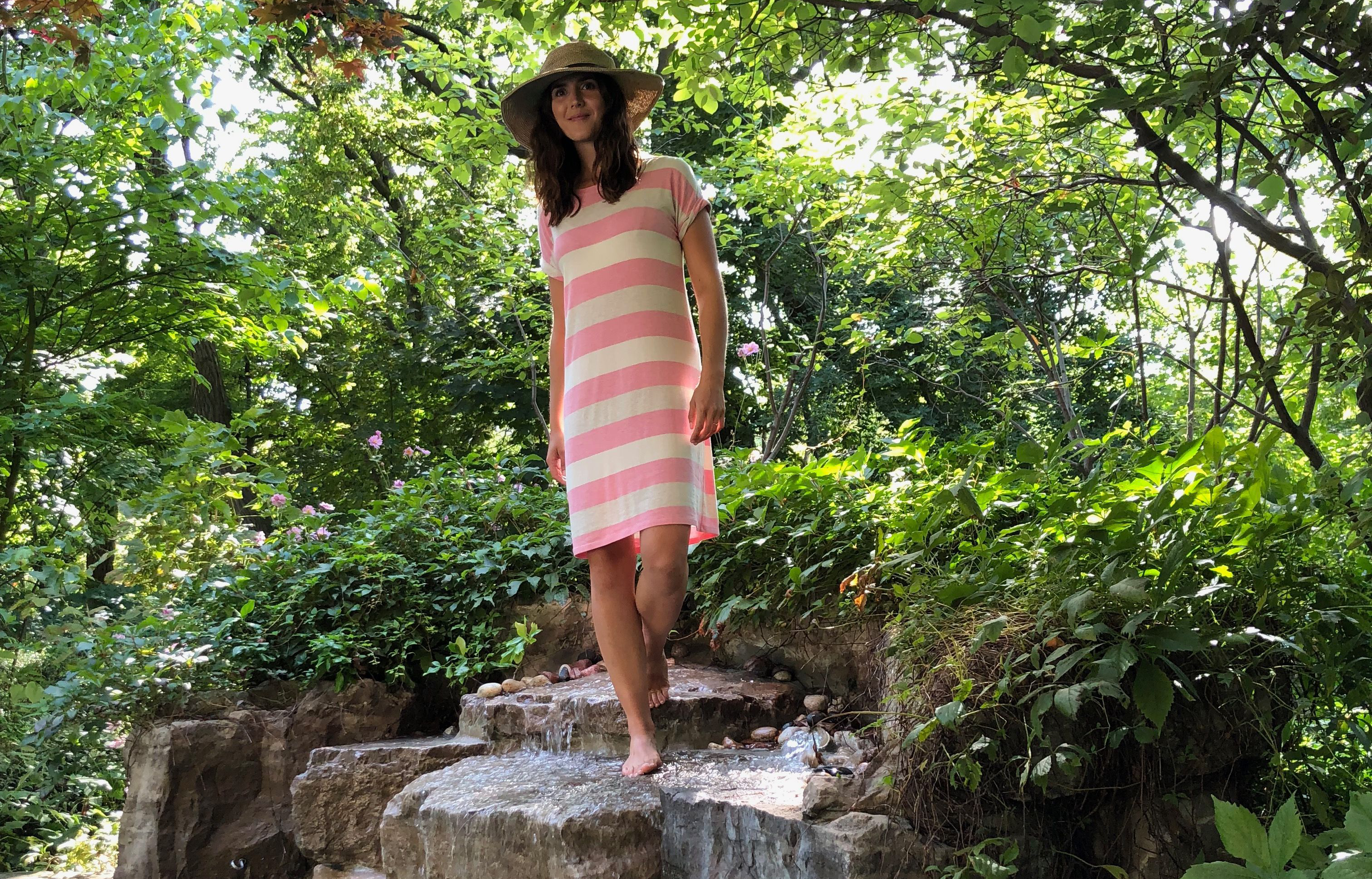 woman out in nature wearing an eco-friendly dress and a sun hat