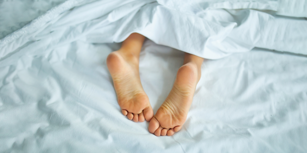 Pieds de filles recouverts de draps de lit blancs