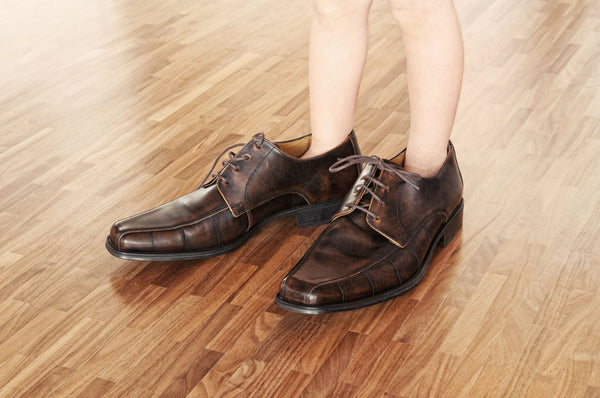 Bambino che indossa scarpe da adulto