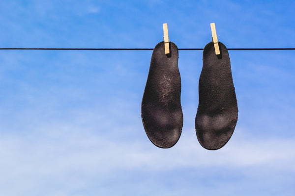 Black insoles drying on laundry clothes
