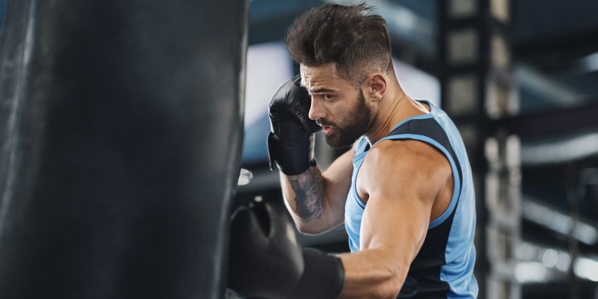 homme actif qui frappe sac de boxe au gym