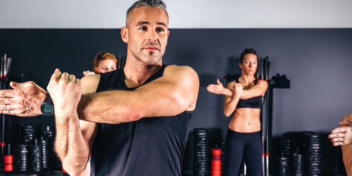 Homme étirant ses bras en classe de remise en forme