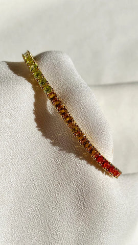 A gold vermeil tennis bracelet featuring a single line of elegant rainbow stones