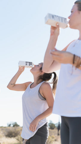 two women drinking water outside