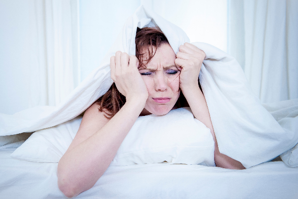 11 Warning Signs and Symptoms of Magnesium Deficiency woman holding pillow over head insomnia