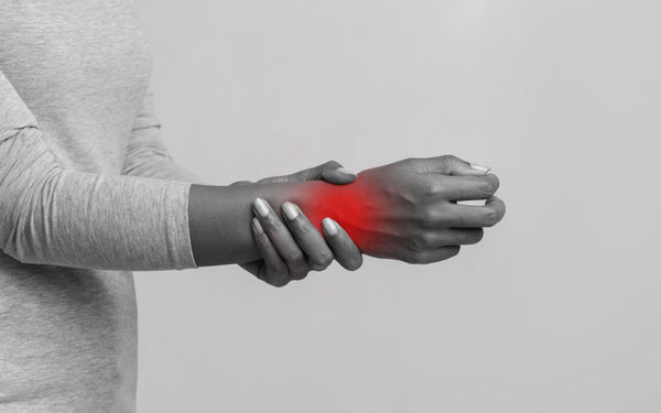 Black and white image of a person holding inflamed wrist, glowing in red