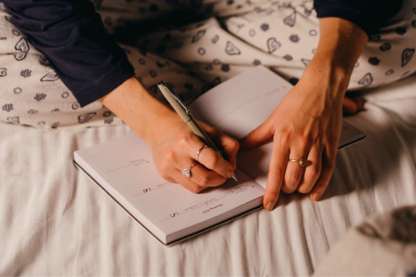 6 tips to avoid flare ups of chronic pain person sitting on bed journaling their chronic pain