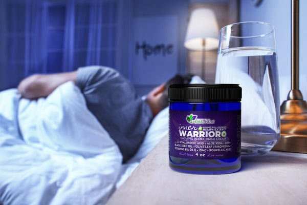 Inner Warrior+ Calming Relief DMSO Cream sitting on nightstand with person sleeping in the background