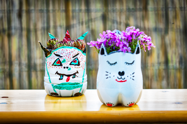 earth day reusing plastic bottles diy crafts with a plastic bottle upcycle it hand painted plastic bottles turned into a monster and a cat planter outside on wooden table