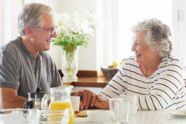 the beginners guide to improving well being elderly couple sitting together at the table happy smiling living well