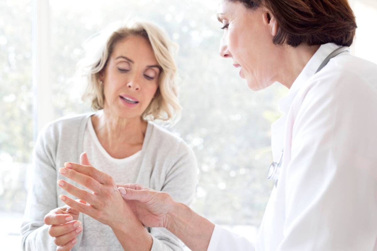 Doctor examines woman's arthritis pain in hand