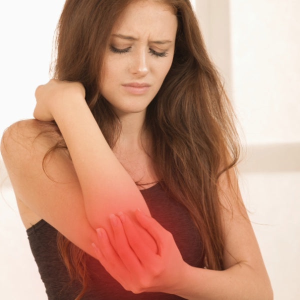 young woman with red hair holding elbow in pain, joint pain