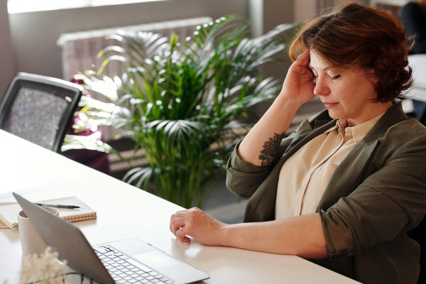 can pain cause high blood pressure woman holding her head in pain sitting at her desk